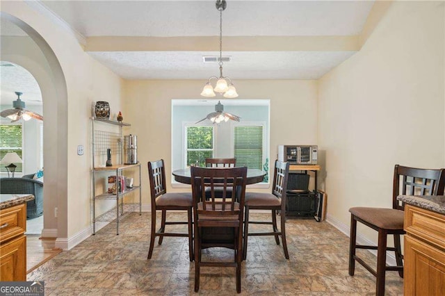 dining space featuring visible vents, baseboards, a ceiling fan, and stone finish flooring