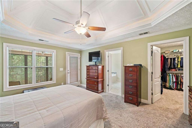 bedroom with visible vents, baseboards, a walk in closet, crown molding, and light colored carpet