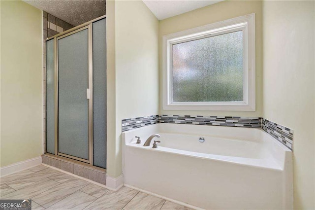 bathroom featuring a bath, a shower stall, and baseboards