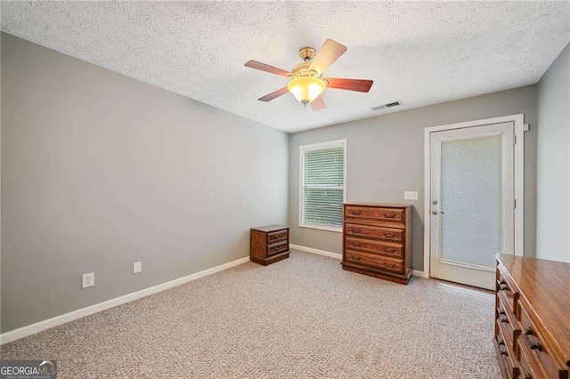 bedroom with visible vents, a textured ceiling, baseboards, light colored carpet, and ceiling fan