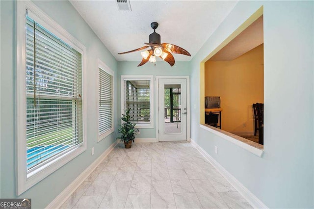 unfurnished sunroom with a ceiling fan and visible vents