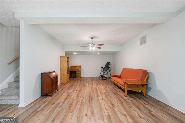 living area with stairway, light wood-style flooring, visible vents, and a textured ceiling