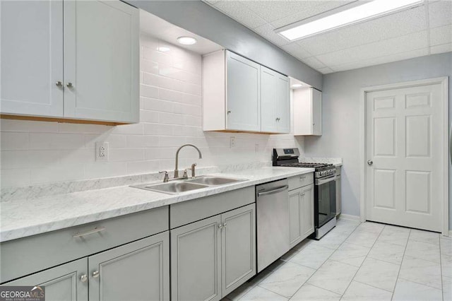 kitchen featuring decorative backsplash, gray cabinets, marble finish floor, stainless steel appliances, and a sink