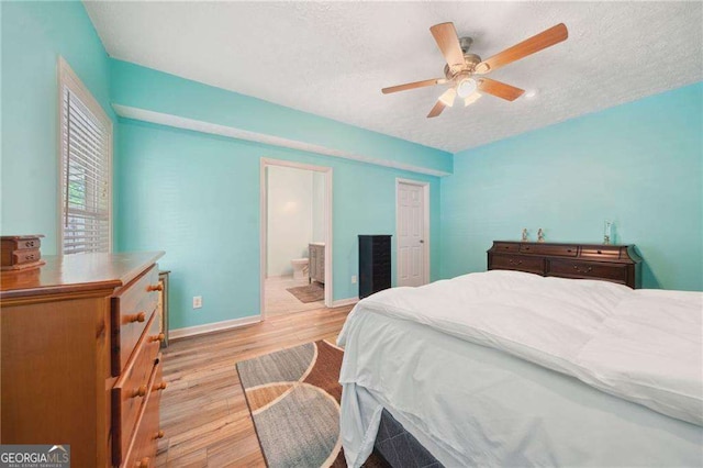 bedroom with a ceiling fan, a textured ceiling, ensuite bath, light wood-style floors, and baseboards