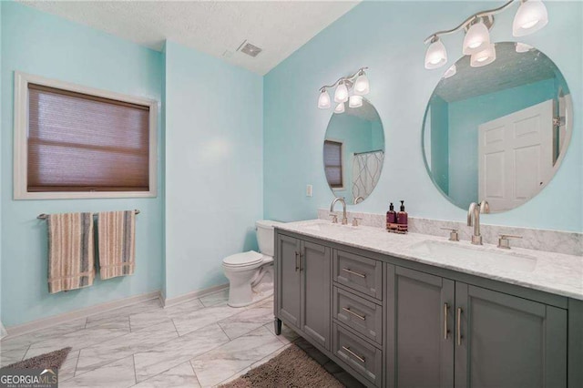 bathroom with a sink, a textured ceiling, marble finish floor, and toilet