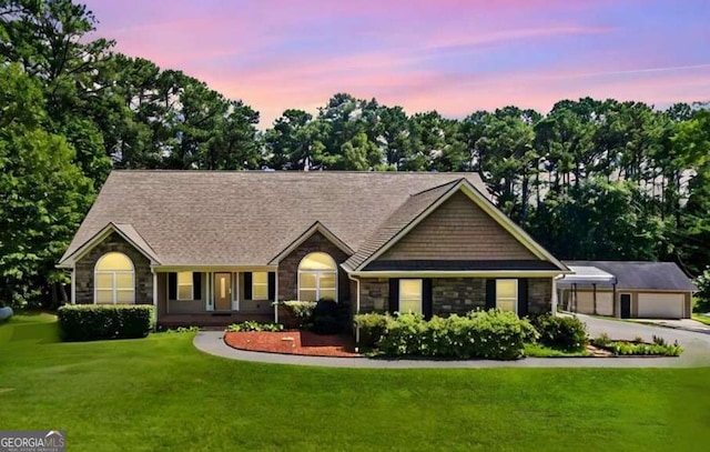 ranch-style home with a front lawn, a garage, stone siding, and an outdoor structure