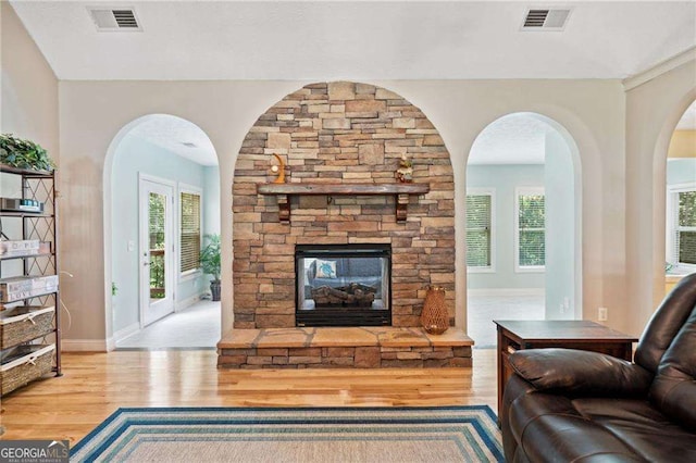 living area with visible vents, a fireplace, baseboards, and wood finished floors