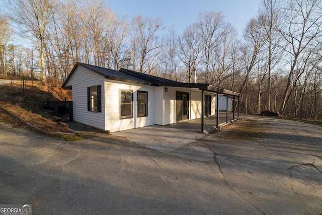 view of front of house featuring a standing seam roof, an attached carport, driveway, and metal roof