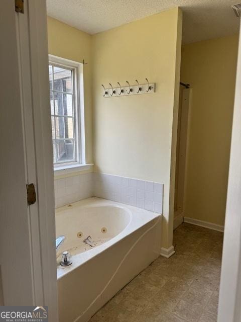 full bathroom featuring walk in shower, baseboards, a textured ceiling, and a tub with jets