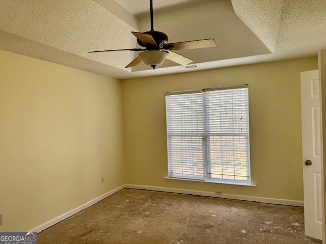 empty room with visible vents, ceiling fan, a textured ceiling, and baseboards