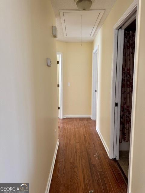 hall featuring attic access, baseboards, and wood finished floors