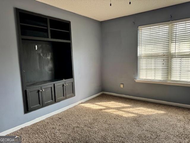 unfurnished living room with carpet, baseboards, and a textured ceiling