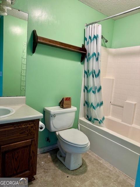 full bath with vanity, shower / tub combo, toilet, and a textured ceiling