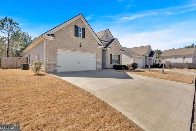 traditional-style house with fence, concrete driveway, an attached garage, brick siding, and central AC unit