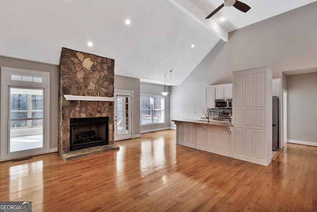 unfurnished living room featuring visible vents, beamed ceiling, ceiling fan, and light wood finished floors