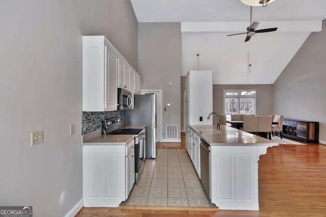 kitchen featuring a peninsula, a sink, appliances with stainless steel finishes, white cabinetry, and a kitchen breakfast bar