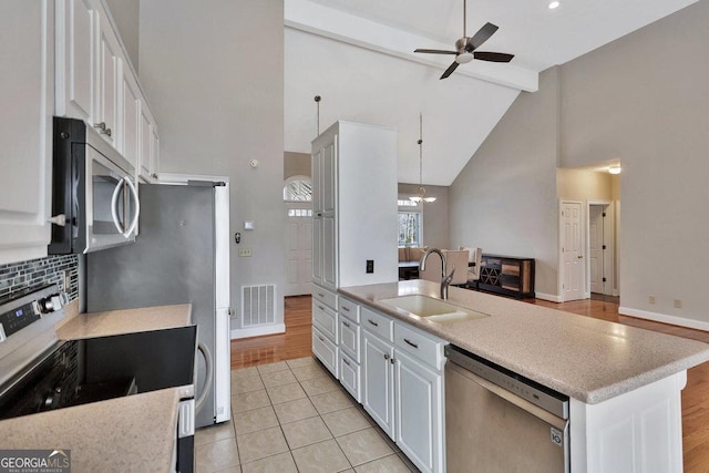 kitchen with visible vents, beamed ceiling, appliances with stainless steel finishes, white cabinets, and a sink