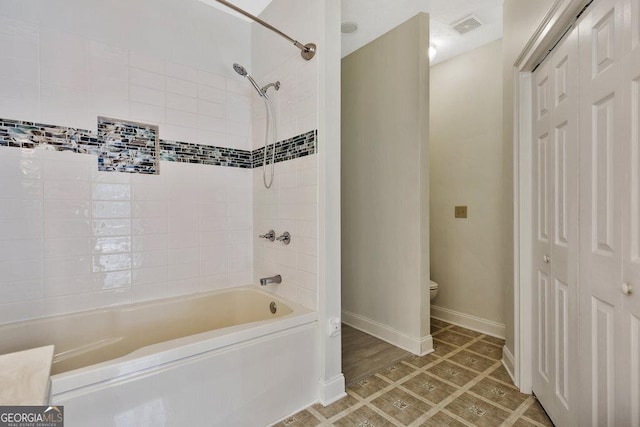 bathroom featuring toilet, baseboards, visible vents, and shower / bath combination