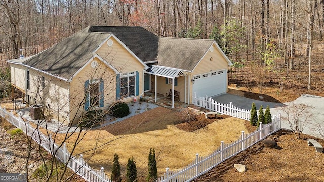 single story home featuring driveway, fence, a forest view, roof with shingles, and a garage