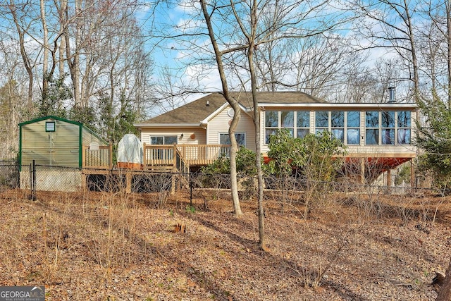 back of house with an outbuilding, a sunroom, and a wooden deck