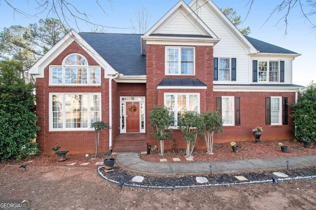 view of front of property featuring brick siding and roof with shingles