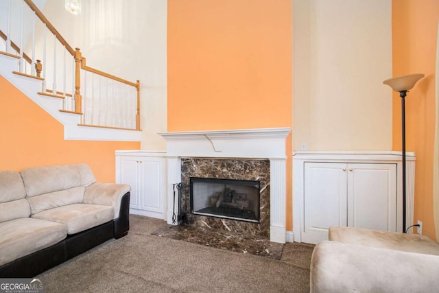 living room featuring stairs, a premium fireplace, and carpet flooring