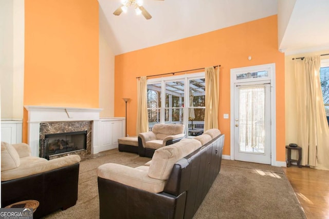 living room featuring a fireplace, a ceiling fan, baseboards, and high vaulted ceiling