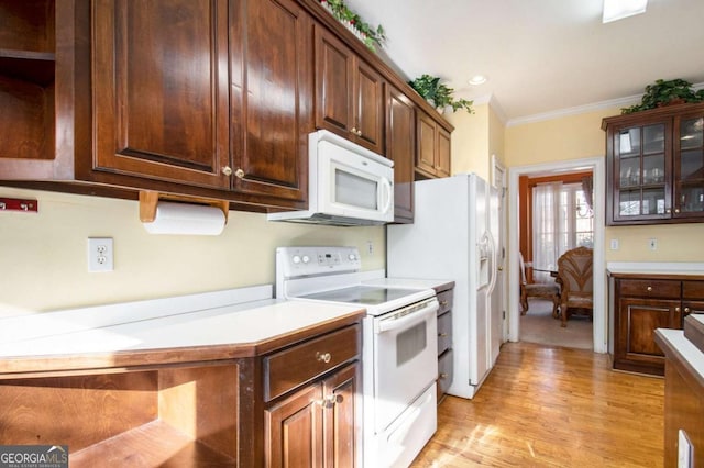 kitchen featuring light wood finished floors, glass insert cabinets, light countertops, ornamental molding, and white appliances