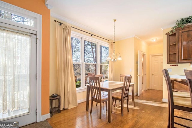 dining area featuring a chandelier, crown molding, light wood-type flooring, and baseboards