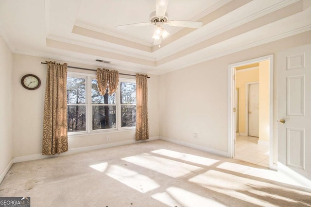 carpeted spare room with a raised ceiling, ornamental molding, visible vents, and ceiling fan