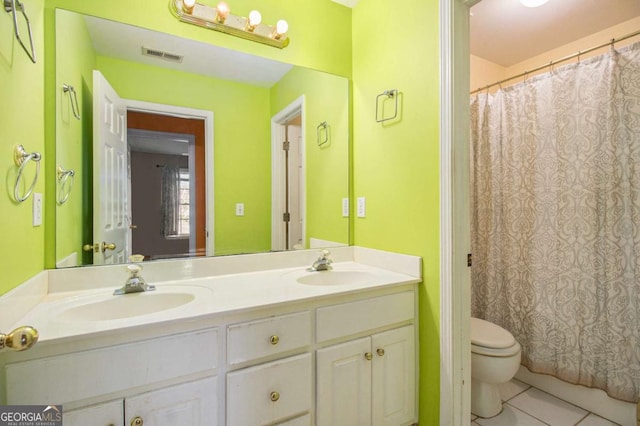 bathroom with visible vents, toilet, double vanity, tile patterned floors, and a sink