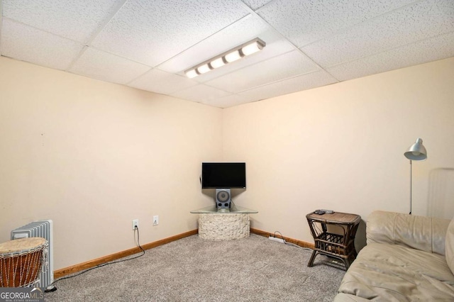 carpeted living area featuring a paneled ceiling and baseboards