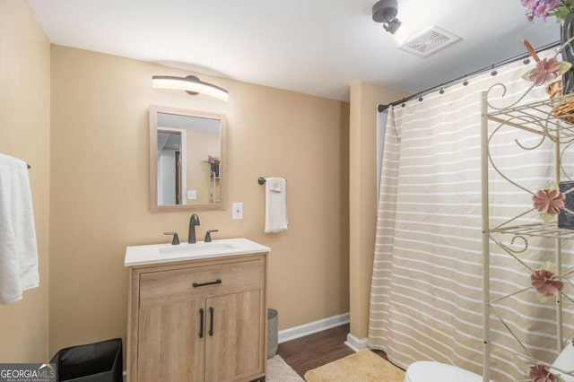 bathroom with visible vents, vanity, baseboards, and wood finished floors