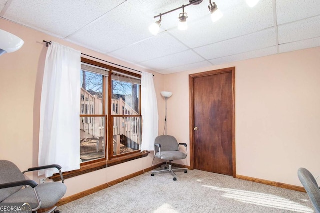 carpeted office space featuring a paneled ceiling and baseboards