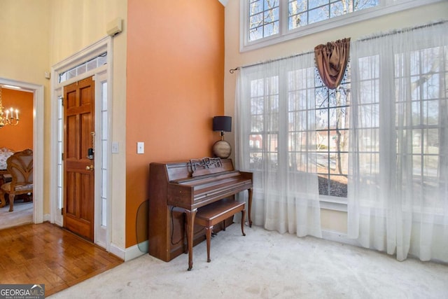 sitting room with a chandelier, baseboards, carpet, and a towering ceiling