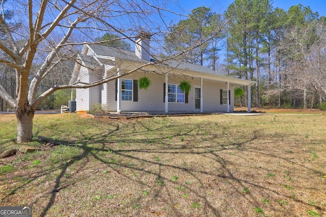 view of front facade featuring a front lawn, central AC, and a chimney