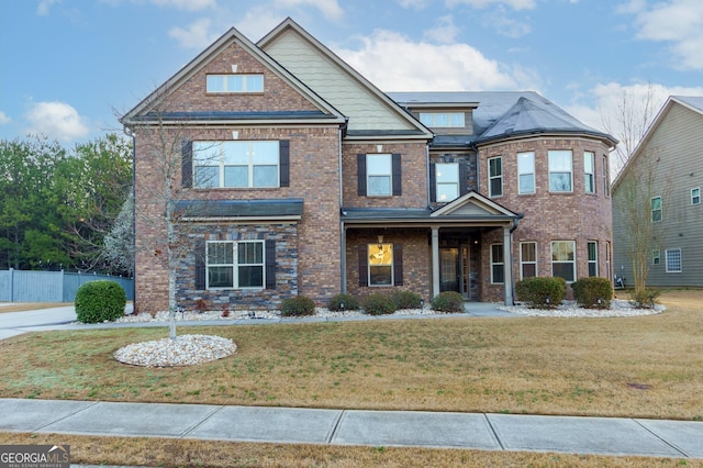 view of front of property featuring a front lawn, fence, and brick siding