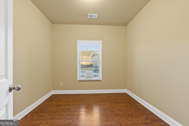 unfurnished room featuring dark wood-style floors, visible vents, and baseboards