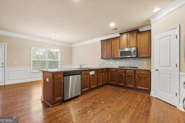 kitchen with a sink, a peninsula, brown cabinets, and stainless steel appliances