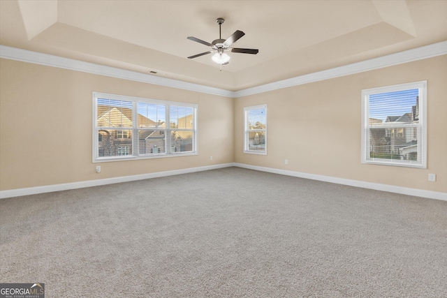 spare room featuring a tray ceiling, baseboards, a ceiling fan, and crown molding