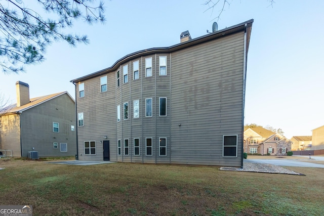 rear view of property with central air condition unit, a yard, and a patio area