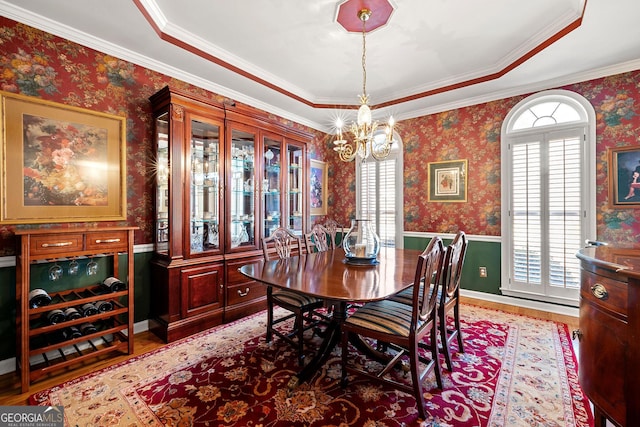 dining room featuring wainscoting, wallpapered walls, and wood finished floors