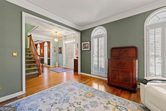 entryway featuring a wealth of natural light, visible vents, stairs, and wood finished floors