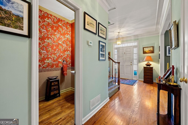 entryway featuring visible vents, baseboards, hardwood / wood-style floors, and crown molding