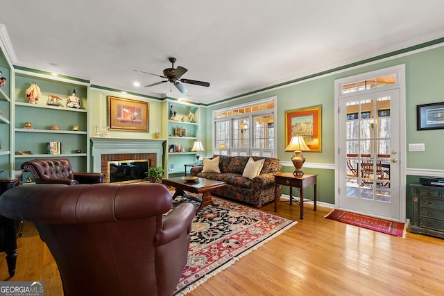 living area featuring plenty of natural light, wood finished floors, a fireplace, and ornamental molding