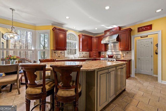 kitchen with a kitchen island, wall chimney exhaust hood, decorative backsplash, stove, and dark brown cabinets