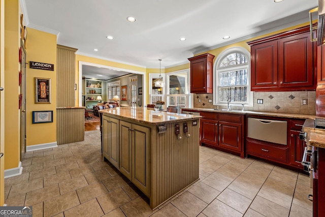 kitchen with dark brown cabinets, a kitchen island, crown molding, light stone counters, and a warming drawer