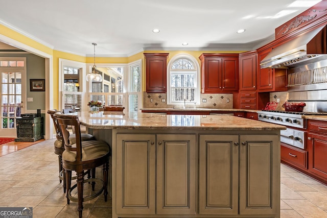 kitchen with exhaust hood, tasteful backsplash, reddish brown cabinets, and a kitchen island