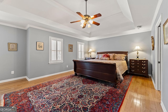 bedroom featuring ornamental molding, a raised ceiling, baseboards, and hardwood / wood-style flooring