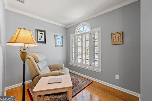 sitting room with baseboards, wood-type flooring, and crown molding